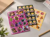 Sticker vinyl sheets stacked with colorful anime illustrations showing vibrant CMYK printing - Sticker Sheet Printing