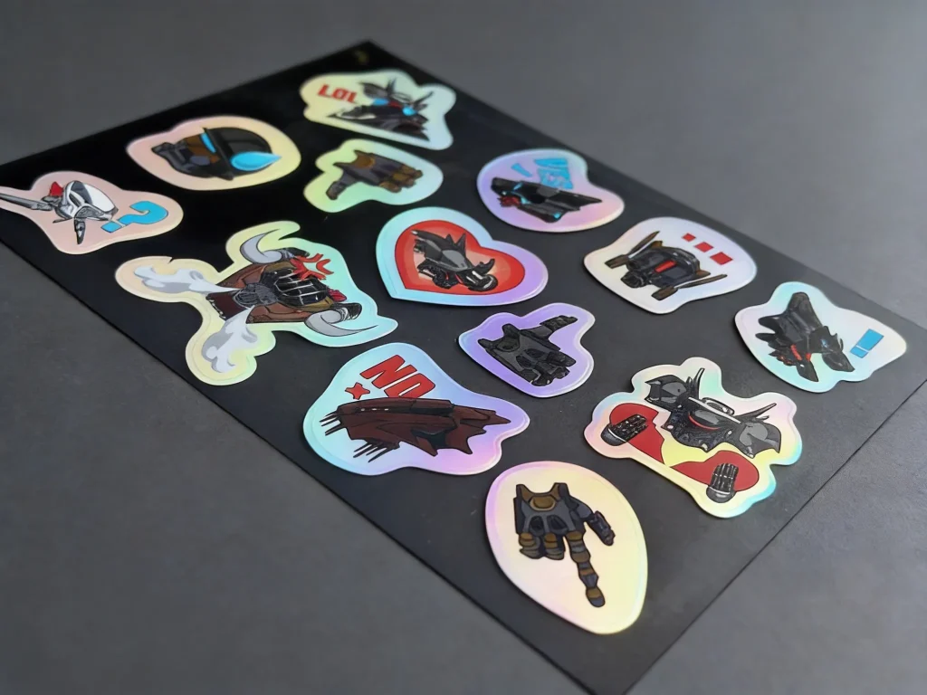 Holographic sticker sheet at angle showing color-shift effect with cute designs - Sticker Sheet Printing